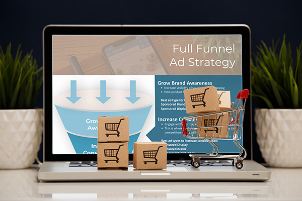 Amazon advertising management services full funnel strategy shown on laptop with cart and boxes sitting on keyboard